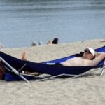 man on beach in portable folding hammock