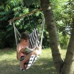 Girl reading book in kids hanging chair