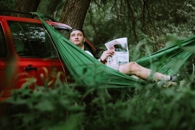 man hanging a hammock from car roof without trees