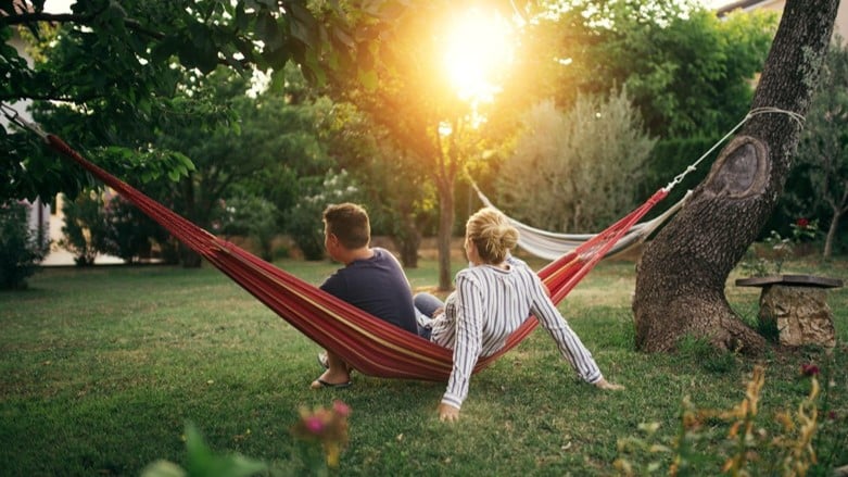 couple sitting on hammock hanging between trees